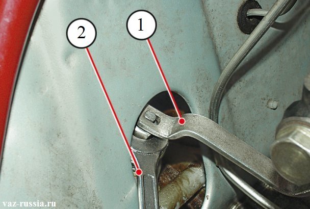 Удерживание специальным ключом под цифрой «1» штока от проворачивания. А гачным ключом в это время под цифрой «2» отворачивание гайки.